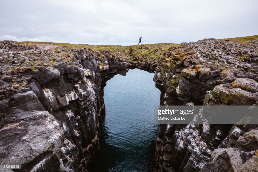 Man on top of natural rocky arch, Snaefellsnes, Iceland