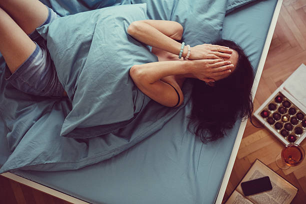 Depressed woman in bed with hands on face